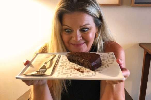 Melissa admiring the world's best chocolate cake at Landeau Chocolate in Chiado, Lisbon. The cake is beautifully decorated with intricate details and a perfect finish, the rich chocolate aroma fills the air and make it clear that it's the best chocolate cake available.