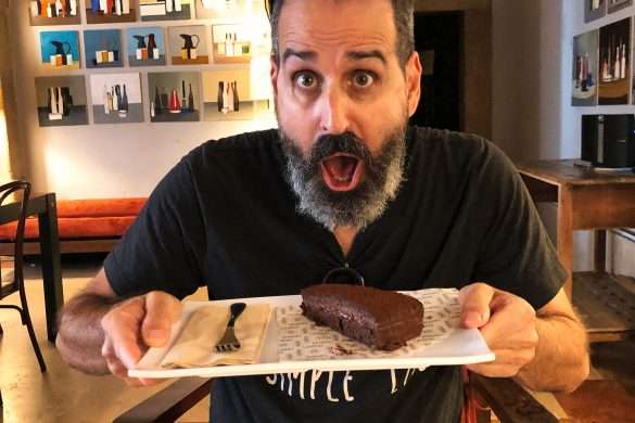 Michael looking at a chocolate cake at Landeau Chocolate in Chiado, Lisbon. The cake is beautifully decorated with intricate details and a perfect finish, making it clear that it's considered the world's best chocolate cake.