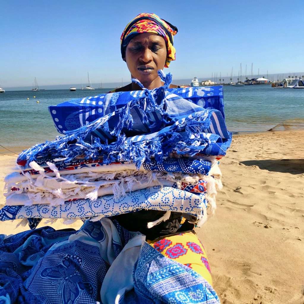 Colorful beach blankets showcased by enthusiastic vendor.