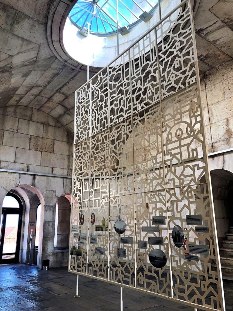 Ornate partition with symbols and patterns, illuminated by a skylight in Lisbon at Rua Augusta Arch.