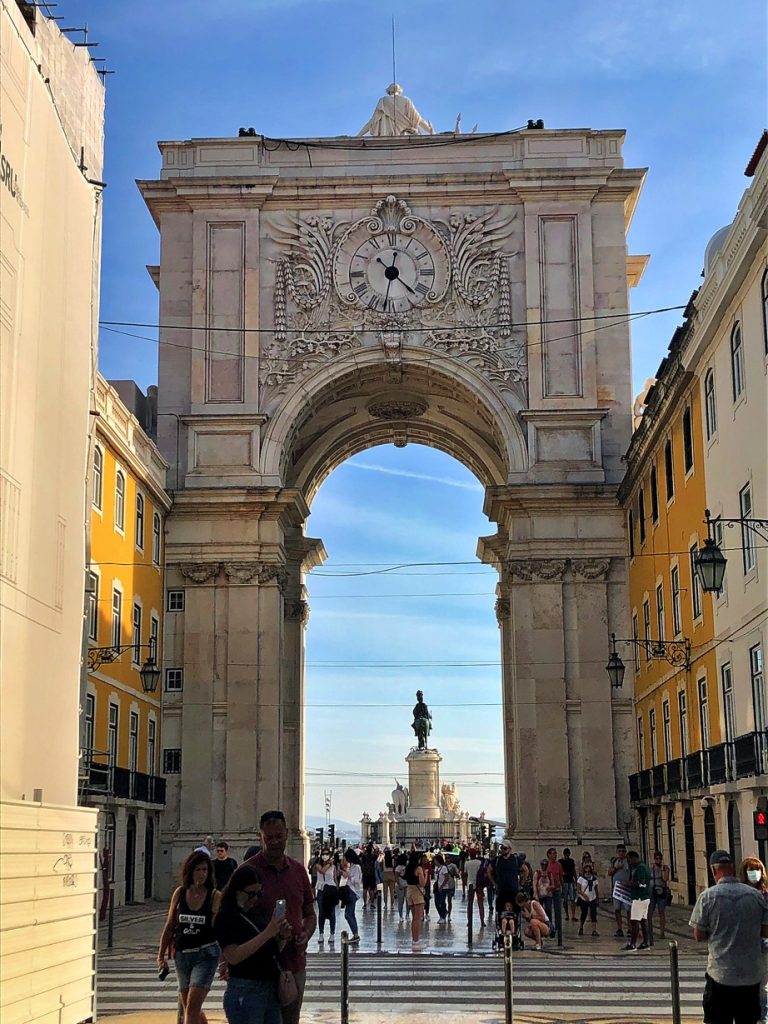Busy street leading to Rua Augusta Arch, teeming with locals and tourists in Lisbon, Portugal.